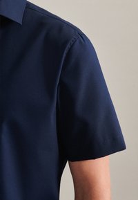 Camicia a maniche corte, blu navy, realizzata in tessuto morbido. Presenta un colletto a punta e cuciture pulite lungo le cuciture.