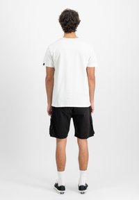 Hvid bomulds t-shirt med rund hals, parret med sorte cargoshorts. Shortsene har sidelommer og en afslappet pasform.