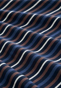 Tissu marine avec des rayures ondulées en bleu foncé, bleu clair, marron et blanc. Texture douce avec une finition lisse.