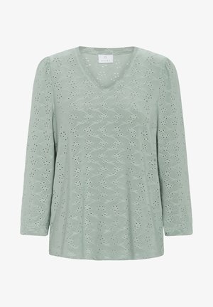 Top verde chiaro a maniche lunghe con scollo a V, caratterizzato da intricate fantasie ritagliate, texture morbida e dettagli arricciati sulle spalle.