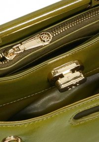 Green leather handbag interior with a gold zipper and clasp. Smooth texture with a glossy finish and contrasting linings for easy access.