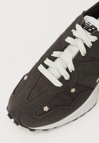 Mørkegrå sneaker med overdel i semsket skinn og stoff, hvite snørebånd og blomsterbroderi som detaljer. Tykkt hvitt mellomsåle og strukturert svart yttersåle.