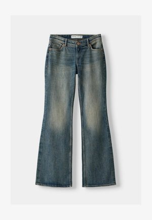 Blaue Schlagjeans mit einem ausgewaschenen Look, fünf Taschen und einem Knopfverschluss. Das Material zeigt eine Denim-Textur mit dezenten Stickdetails.