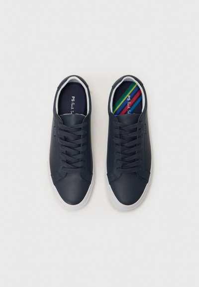 Navy blue sneakers with a smooth, synthetic upper, white rubber sole, and flat laces. Inside features a multicolored striped insole.