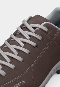 Καφέ καθημερινό παπούτσι με λευκά κορδόνια, λευκή διακοσμητική ραφή και γκρι εσωτερική επένδυση σε λευκή σόλα.