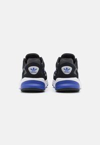 Schwarze Sportschuhe mit einem strukturierten Mesh-Obermaterial, einer weißen Zwischensohle und einem blauen Akzent an der Ferse, mit einem Adidas-Logo auf der Rückseite.