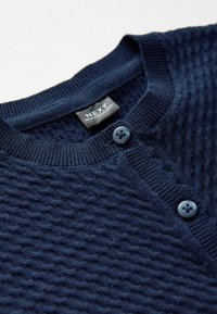 Marineblauwe gebreide cardigan met een gestructureerd patroon, geribde kraag en twee ronde knopen. Het label vermeldt "NEXT, gemaakt in Bangladesh."