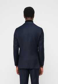 Marineblazer mit maßgeschneiderter Passform, einem einzelnen Rückenschlitz und geknöpften Manschetten. Glatter Stoff mit minimaler Struktur, entworfen für ein formelles Erscheinungsbild.