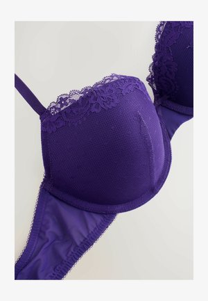 Pura lins spēcīgi uzsvērtā krūšturis ar veidnēm, sieta tekstūru, regulējamiem siksniņām un gludu apakšējo joslu. Sīkākas ziedu akcenti gar augšējo malu.