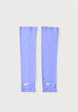 Paire de manches de bras Nike violet clair avec logos swoosh blancs, posées à plat sur un fond blanc.