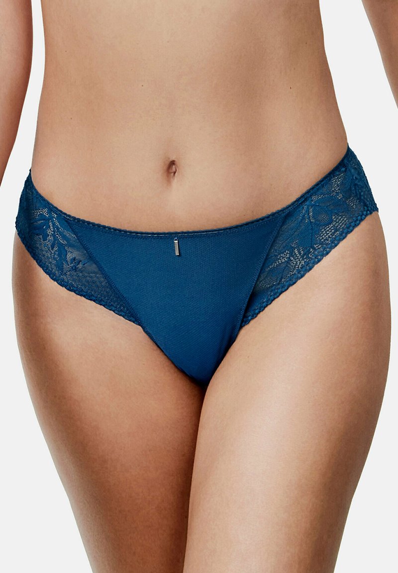 String en dentelle et maille teal avec des bordures en dentelle florale et un petit détail métallique au centre avant. Texture douce et design taille basse.