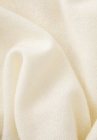 Tejido de punto suave, de color crema, con pliegues suaves y una superficie lisa, ligeramente texturizada.