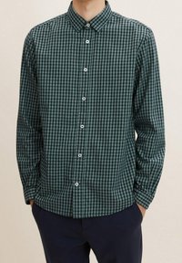 Camicia a maniche lunghe a scacchi verdi e neri con colletto button-down e bottoni frontali, caratterizzata da una vestibilità comoda e un tessuto testurizzato.