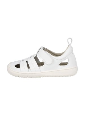 Sandalia blanca de punta cerrada con correa ajustable de Velcro, laterales recortados, suela acolchada y lazo en el talón para facilitar su puesta.