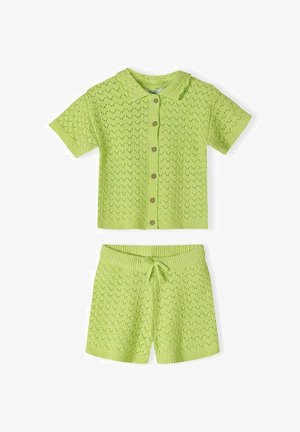 Top verde deschis tricotat cu mâneci scurte și nasturi, cu guler, asortat cu pantaloni scurți cu șnur, având un model delicat cu ochiuri.