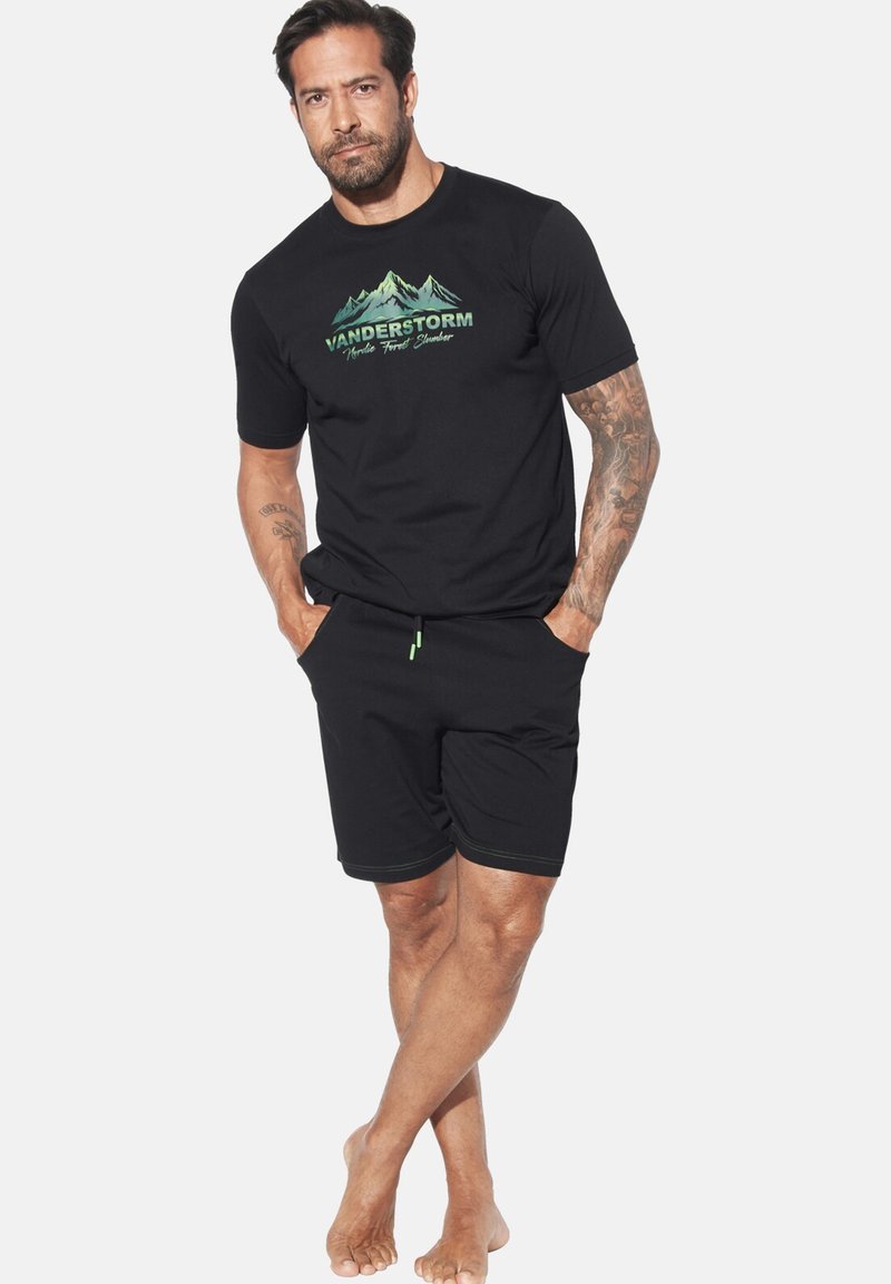 Black cotton t-shirt with green mountain graphic; paired with black shorts featuring an elastic waistband and contrasting stitch detail.
