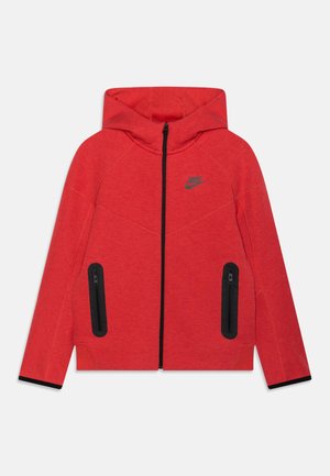 Giacca rossa con cappuccio in tessuto testurizzato, caratterizzata da una cerniera nera e due tasche con zip con dettagli neri. Logo Nike sul petto.