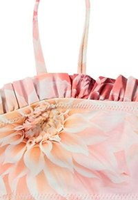 Blommönstrad topp i mjuk rosa tyg, med volangaccent vid halsringningen. Justerbara spännen och en slät yta.