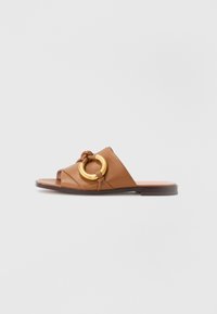 Brune lærerslide sandaler med en knyttet stropp og en stor gullsirkel aksent. Flat såle med minimalistisk design. Åpen tå stil.