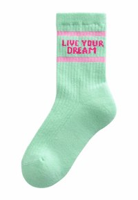 Metinasto mintnozeleni nogavici z roza črtami in besedilom "ŽIVI SVOJ SANJ" v krepki, ponavljajoči se zanki blizu manšete.