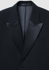 Schwarze Smokingjacke mit Satinrevers, Ein-Knopf-Verschluss und einer Brusttasche. Glatte Textur und scharf geschnittenes, maßgeschneidertes Design.