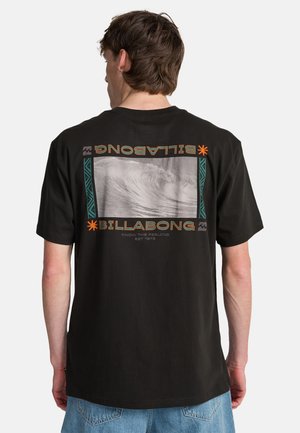 T-shirt nera in cotone con stampa grafica di un'onda, bordata da un design turchese e arancione, con il logo "BILLABONG" al centro.