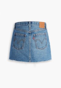 Mini-jupe en jean bleu avec deux poches arrière, passants pour ceinture, ourlet effiloché et patch en cuir marron à la taille.