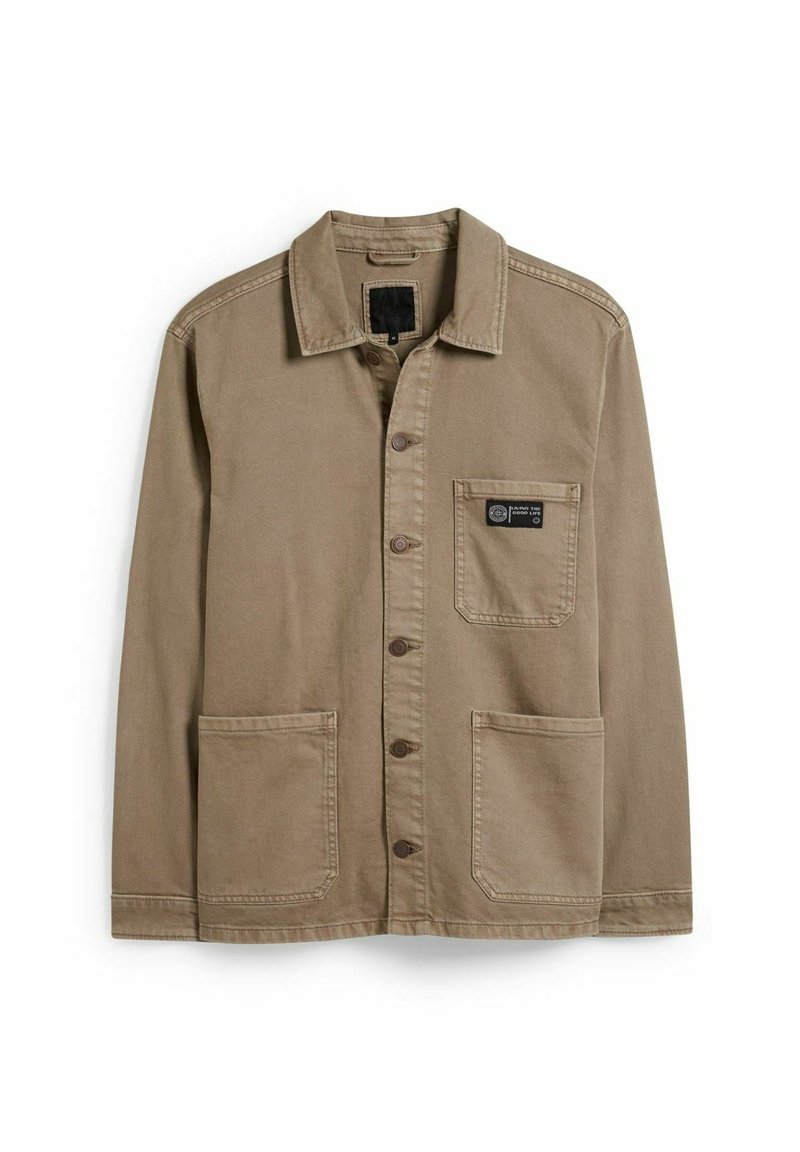 Beżowa bawełniana kurtka z kołnierzykiem, zapięciem na guziki z przodu, dwoma dużymi kieszeniami oraz naszywką z logo na kieszeni na piersi.