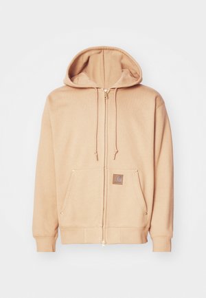 Bežová mikina na zips vyrobená z jemnej látky, so sťahovacou kapucňou, prednými vreckami so zlatými akcentmi a hnedou nášivkou loga.
