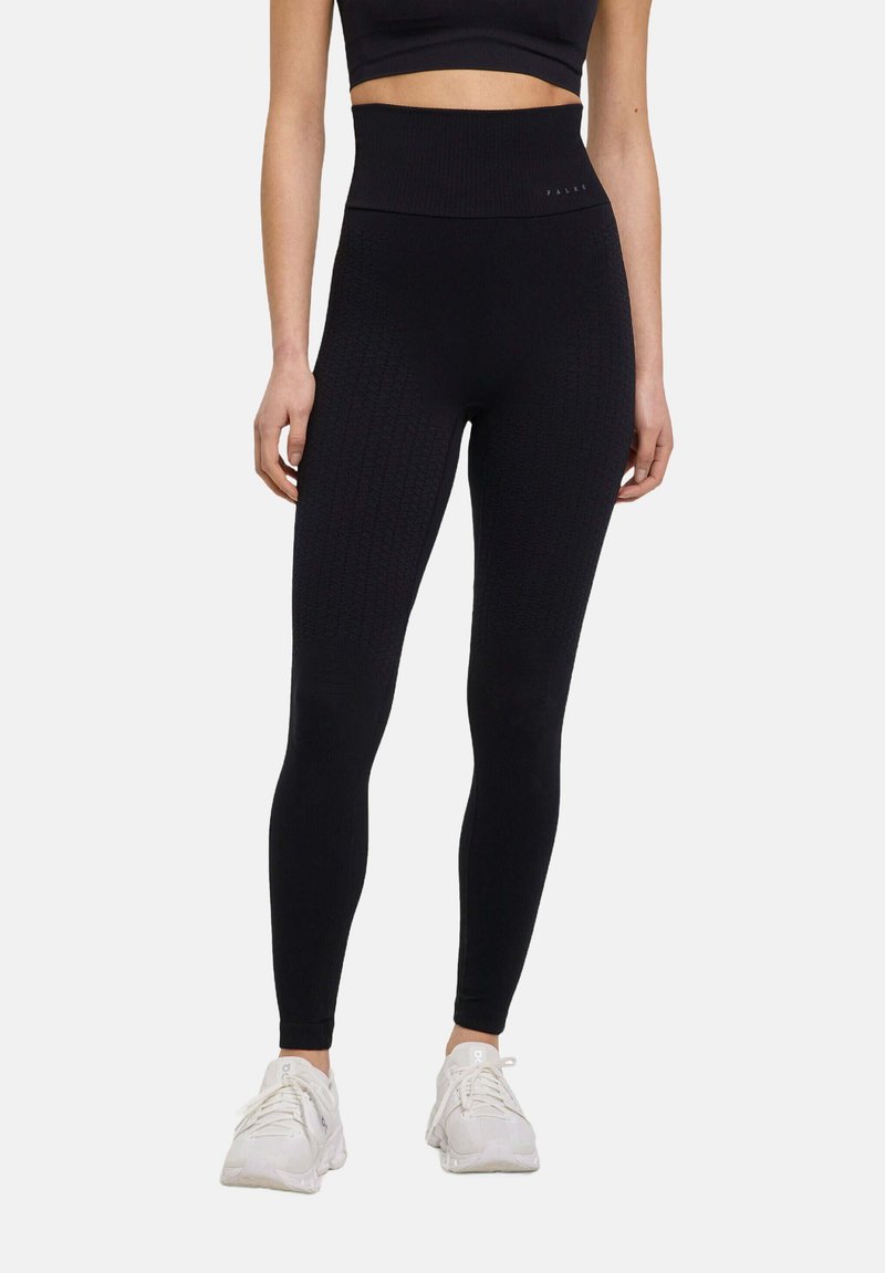 Black high-waisted leggings with textured knit pattern and reinforced waistband, paired with white athletic shoes.