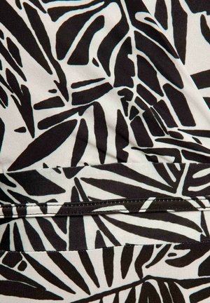 Tissu noir et blanc avec un motif de feuilles abstraites et des coutures visibles le long d'une couture.