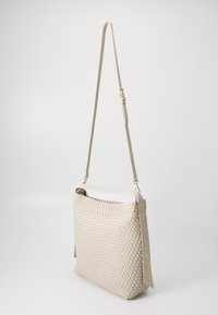 Beige woven leather bag with a flat rectangular shape, adjustable long strap, and a smooth top edge. Features subtle logo accent.