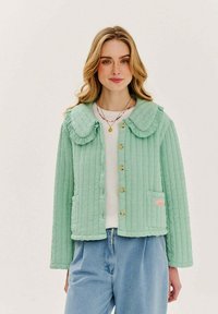 Světle zelená prošívaná bunda s velkým kulatým límcem, zapínáním na knoflíky a dvěma kapsami. Materiál má strukturovaný vzor.