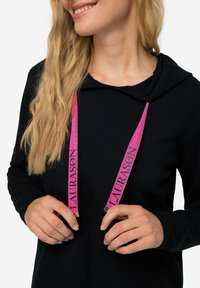I lacci rosa con il marchio "LAURASØN" pendono da un felpa con cappuccio nera. Il tessuto appare morbido con una texture liscia.