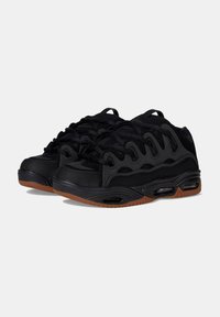 Scarpe sportive nere con tomaia testurizzata, inserti in rete e suole in gomma con ammortizzazione ad aria. Accenti marroni sulla suola.