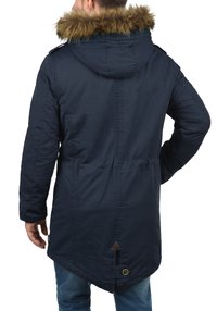 Parka bleu marine avec capuche bordée de fourrure, dotée d'une taille à cordon de serrage, d'un ourlet incliné et de détails à boutons, fabriquée en matériau texturé et résistant à l'eau.