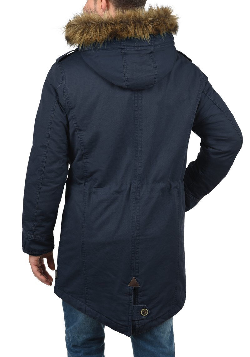 Parka bleu marine avec capuche bordée de fourrure, dotée d'une taille à cordon de serrage, d'un ourlet incliné et de détails à boutons, fabriquée en matériau texturé et résistant à l'eau.