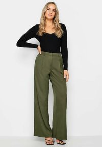 Zwarte geribbelde langemouwen top gecombineerd met olijfgroene hoge taille wijde broek. De outfit heeft een zachte textuur en een naadloos ontwerp.