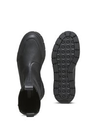 Mustat nahkasaappaat nilkkapituiset, joissa on sileä pinta, joustavat sivut ja kestävä kumipohja, jossa on geometrinen kuvio.