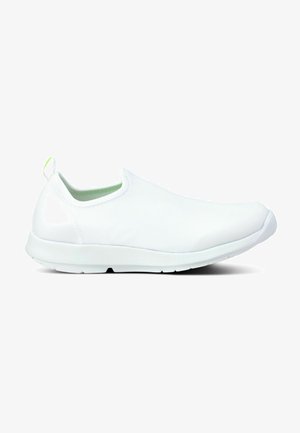 White slip-on shoes with a textured upper, rounded toe, and rubber sole. Features a green accent loop on the heel for easy wear.