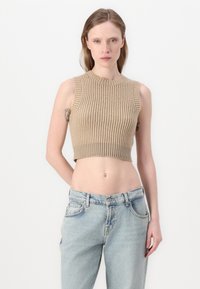 Un crop top sans manches à col haut en ribbed beige, associé à un jean taille haute bleu clair avec fermeture à bouton et poches avant.