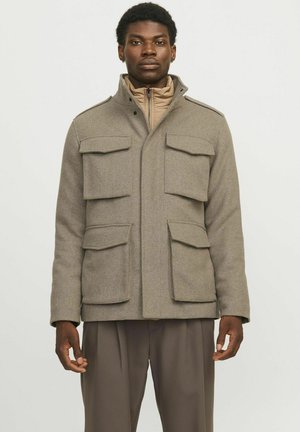 Veste en laine kaki avec quatre poches avant, col haut et fermeture éclair. Design superposé avec doublure intérieure beige et pantalon marron.