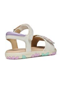 Sandalias de cuero blanco con detalles en púrpura, suela con estampado floral, tiras de Velcro y diseño abierto para mayor transpirabilidad. Detalles Béx en la tira.