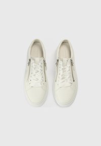 Λευκά αθλητικά παπούτσια από λείο δέρμα, με φερμουάρ στα πλάγια, επίπεδα κορδόνια και υφή από καουτσούκ στην σόλα.