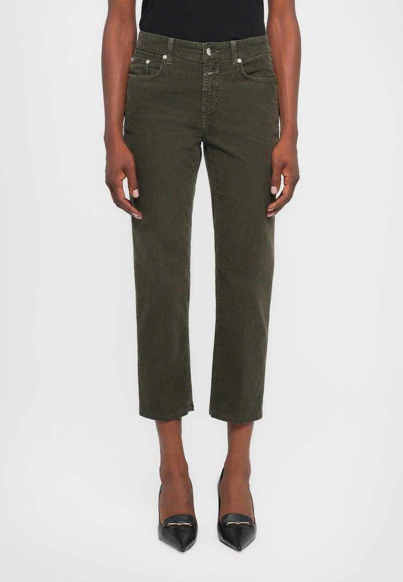 Olive green corduroy cropped pants with front pockets and a button closure, paired with black pointed-toe heels for contrast.