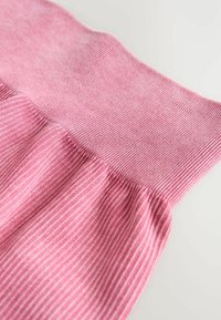 Tela rosa acanalada con una pretina texturizada ligeramente acampanada. Presenta rayas verticales y un acabado suave, creando un aspecto delicado.