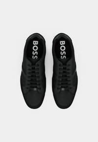 Zwarte sneakers met een gladde bovenkant van stof, ronde neus en platte veters. Beschikt over subtiele branding op de binnenzool en slanke ontwerp lijnen.