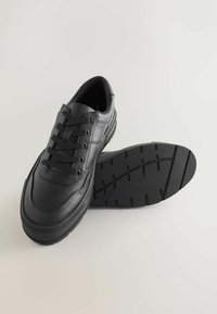 Czarne skórzane sneakersy z teksturowaną powierzchnią, klasyczny design na sznurowadła i wyściółką wokół kostki. Gumowa podeszwa ma bieżnik zapewniający przyczepność.