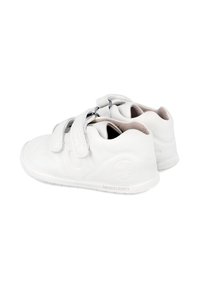 Zapatos blancos para niños con una textura de cuero suave, con puntas redondeadas y suelas planas, que cuentan con dos correas de Velcro para un ajuste seguro.