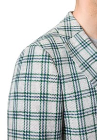 Teksturowany, jasnoszary żakiet z zielono-niebieskim wzorem w kratkę, z wyraźnie zarysowanymi ramionami i klapami w stylu notch.